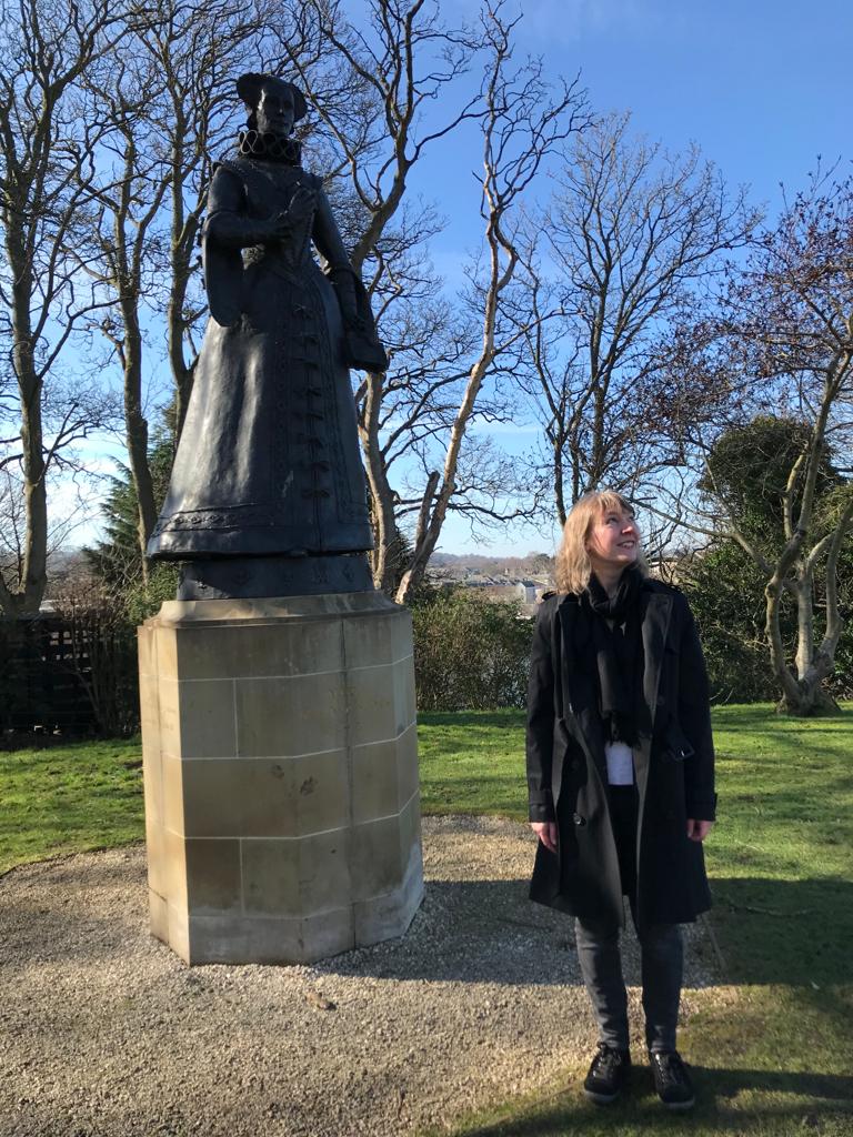 Jennifer Morag Henderson standing by the statue of Mary, Queen of Scots at Linlithgow Palace